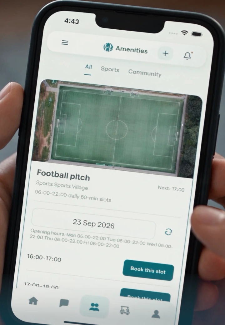 A phone showing the Amenities screen, with the football pitch open and a Book this slot button